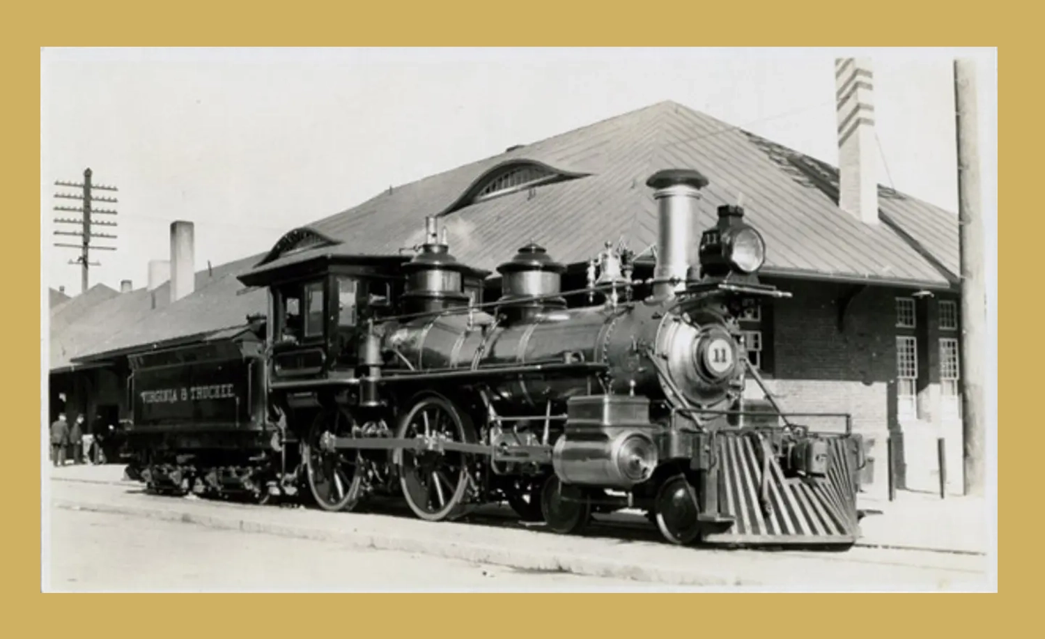 A train is parked on the tracks near a building.